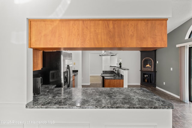 4405 Plumosa St, Spring Hill, FL 34607 - kitchen featuring brown cabinetry, dark stone counters, a fireplace, and appliances with stainless steel finishes