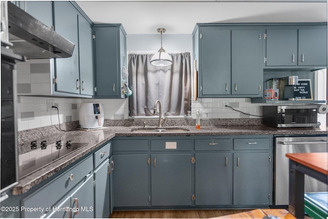kitchen featuring a sink, stainless steel microwave, decorative backsplash, black electric stovetop, and under cabinet range hood