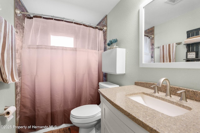 full bath featuring a shower with curtain, toilet, a textured wall, and vanity