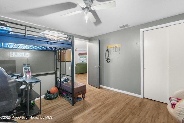 bedroom featuring baseboards, a ceiling fan, wood finished floors, and visible vents