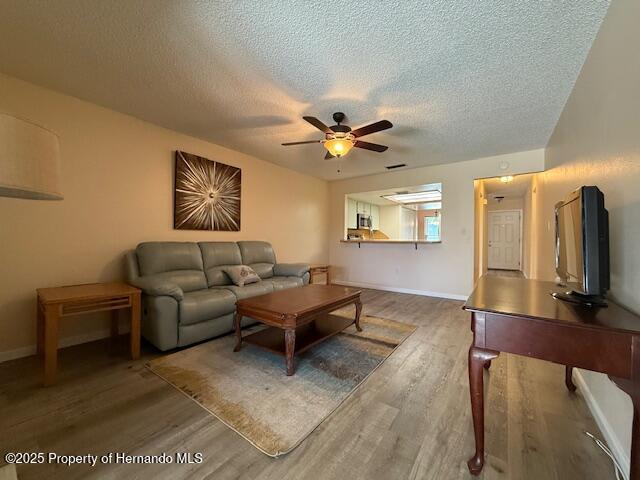 947 Village Dr, Brooksville, FL 34601 - living area with wood finished floors, ceiling fan, a textured ceiling, and baseboards
