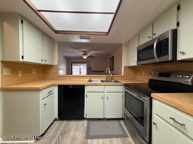 947 Village Dr, Brooksville, FL 34601 - kitchen with stainless steel appliances, a sink, light wood-style floors, ceiling fan, and decorative backsplash