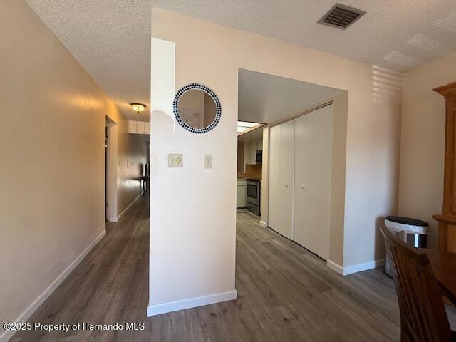 947 Village Dr, Brooksville, FL 34601 - hall with wood finished floors, a textured ceiling, and baseboards