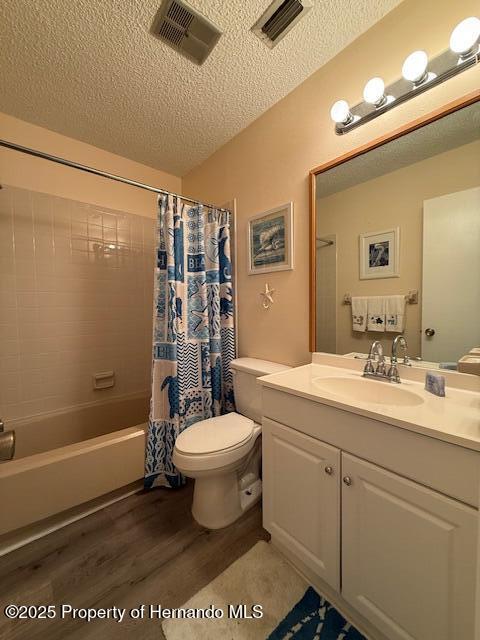 947 Village Dr, Brooksville, FL 34601 - bathroom with wood finished floors, toilet, a textured ceiling, shower / bathtub combination with curtain, and vanity