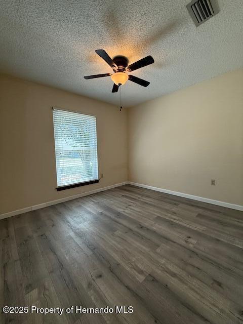 947 Village Dr, Brooksville, FL 34601 - empty room with a textured ceiling, ceiling fan, wood finished floors, and baseboards