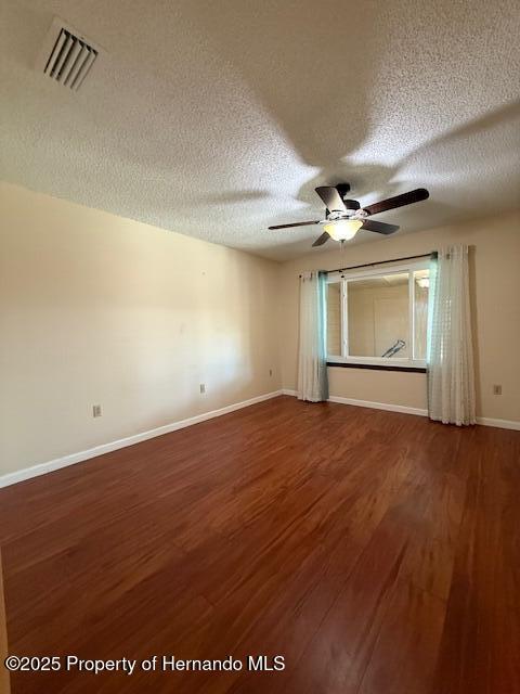 947 Village Dr, Brooksville, FL 34601 - spare room with a textured ceiling, a ceiling fan, wood finished floors, and baseboards