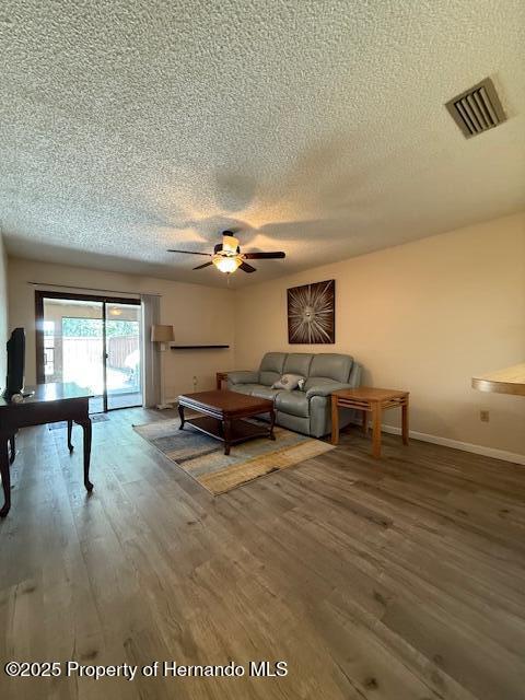 947 Village Dr, Brooksville, FL 34601 - living area with a textured ceiling, wood finished floors, a ceiling fan, and baseboards