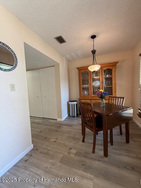 947 Village Dr, Brooksville, FL 34601 - dining space with baseboards, wood finished floors, and a textured ceiling
