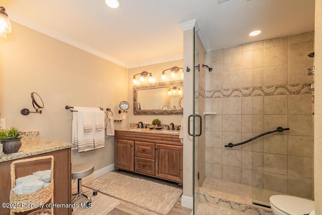full bathroom with a stall shower, toilet, baseboards, crown molding, and vanity