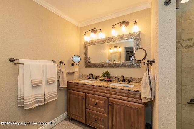 full bath with a textured wall, crown molding, a sink, and double vanity