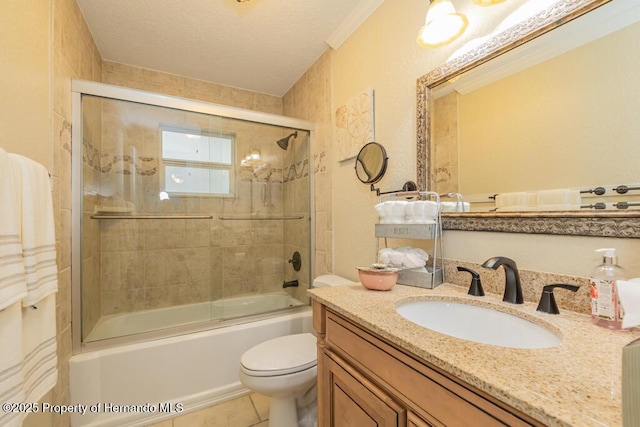 bathroom with tile patterned flooring, combined bath / shower with glass door, toilet, vanity, and a textured ceiling