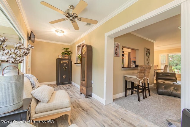 sitting room with baseboards, wood finished floors, visible vents, and crown molding
