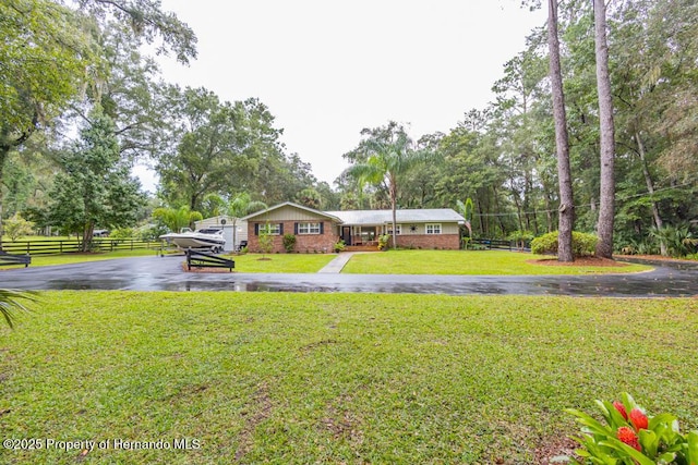 view of front of home featuring a front lawn, fence, and driveway