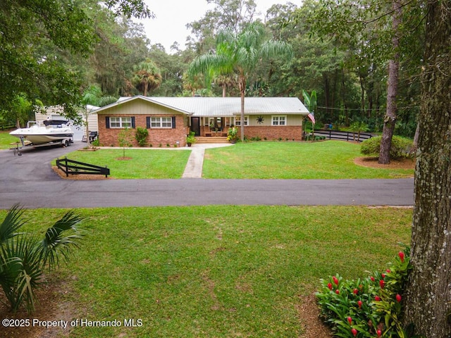 ranch-style home featuring fence, brick siding, and a front yard