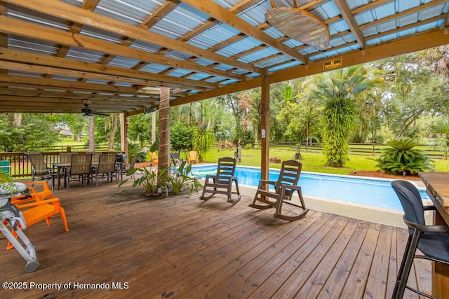 deck with outdoor dining area, an outdoor pool, and a yard