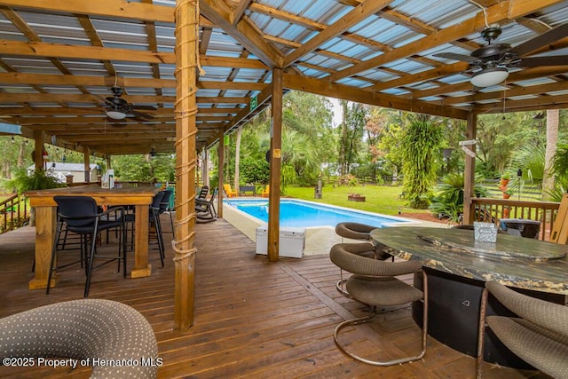 pool with outdoor dining area, a yard, a deck, and ceiling fan