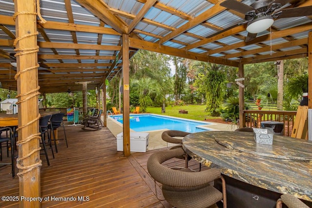 outdoor pool featuring a lawn, outdoor dry bar, a wooden deck, and ceiling fan