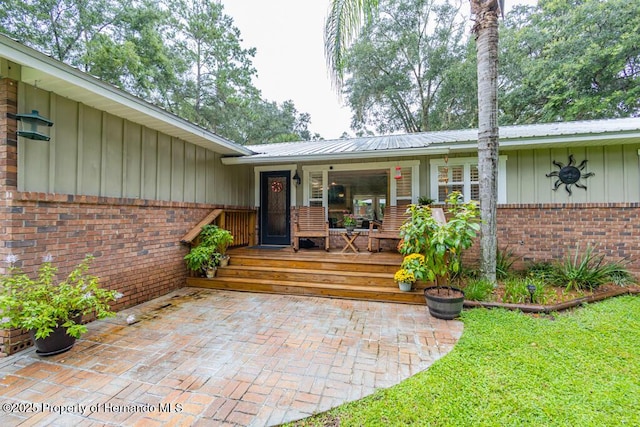 property entrance with board and batten siding, covered porch, and brick siding