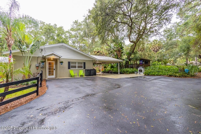 ranch-style home with stucco siding, aphalt driveway, fence, and an attached carport