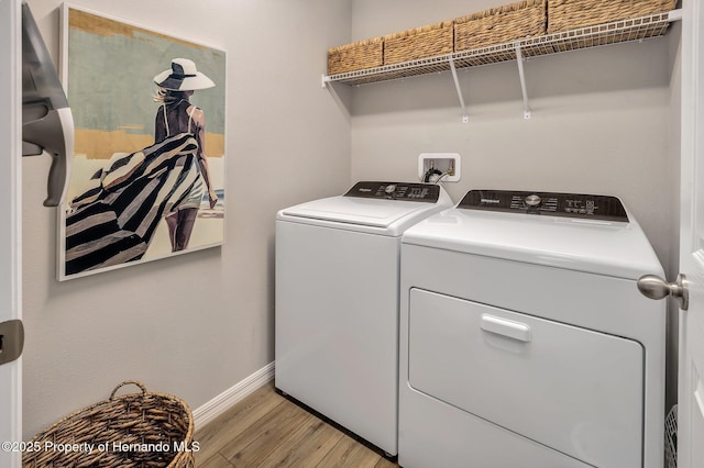 clothes washing area featuring washing machine and clothes dryer, light wood-style flooring, laundry area, and baseboards