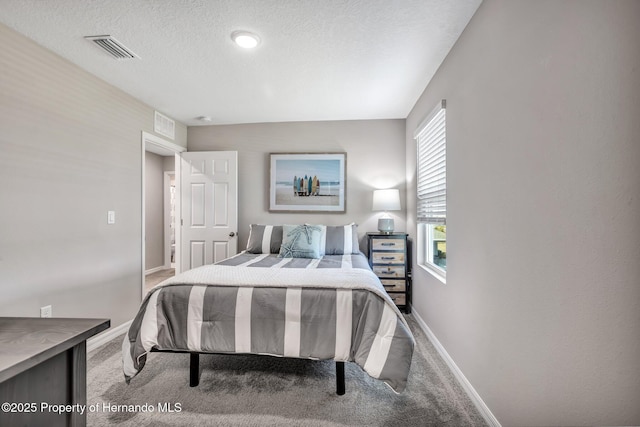 carpeted bedroom with a textured ceiling, visible vents, and baseboards