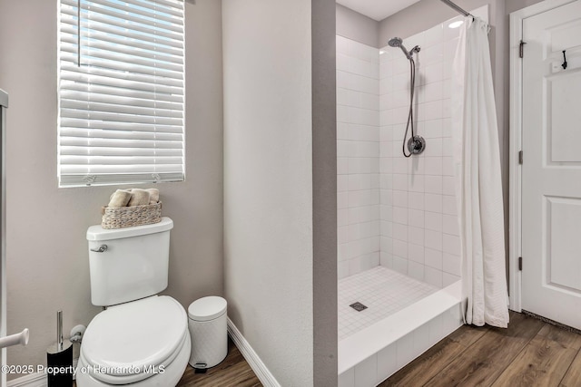 bathroom featuring wood finished floors, a shower stall, and toilet