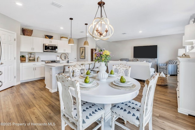 dining space with a chandelier, light wood-style floors, recessed lighting, and visible vents