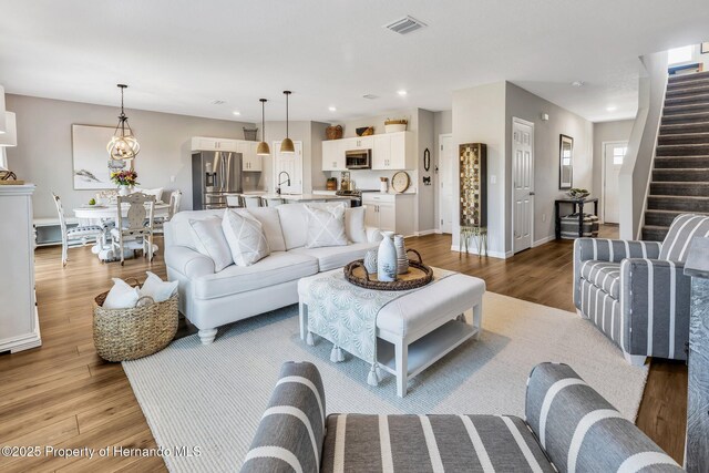 living area featuring stairway, light wood-style floors, visible vents, baseboards, and recessed lighting