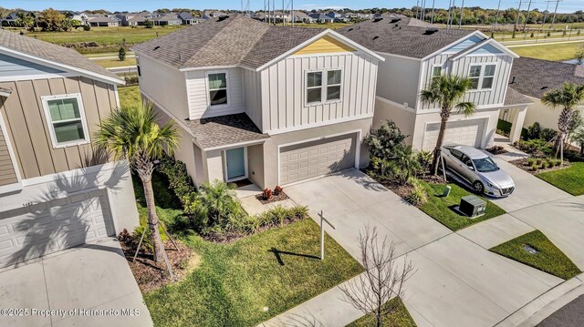 view of front of house with board and batten siding, a shingled roof, a residential view, concrete driveway, and an attached garage