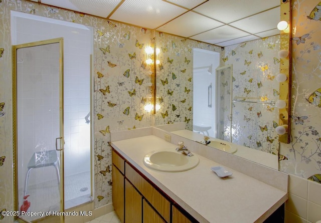 full bath featuring wallpapered walls, a shower stall, and vanity