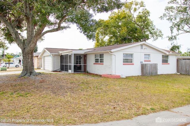 back of property with a sunroom, fence, a yard, and a garage