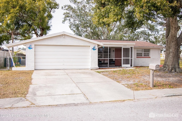 ranch-style home featuring fence, concrete driveway, brick siding, a sunroom, and a garage