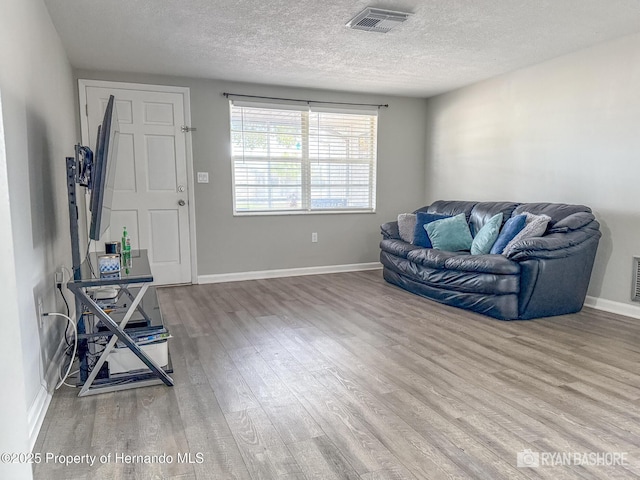 sitting room with baseboards, wood finished floors, visible vents, and a textured ceiling