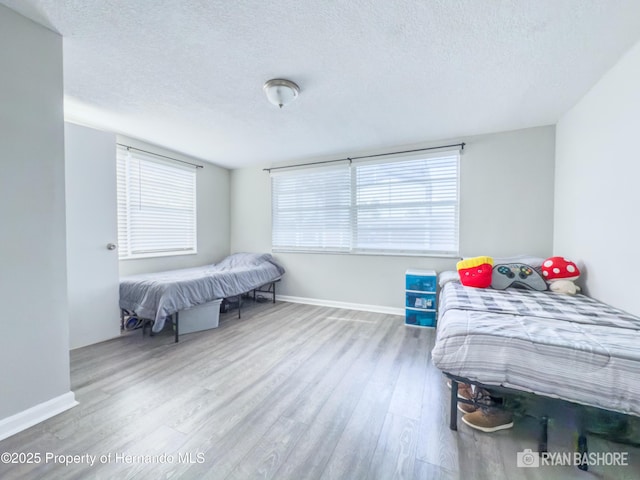 bedroom with wood finished floors, a textured ceiling, and baseboards