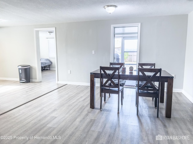 dining space featuring baseboards, wood finished floors, and a textured ceiling