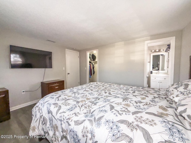bedroom featuring dark wood-style flooring, visible vents, baseboards, a spacious closet, and a closet