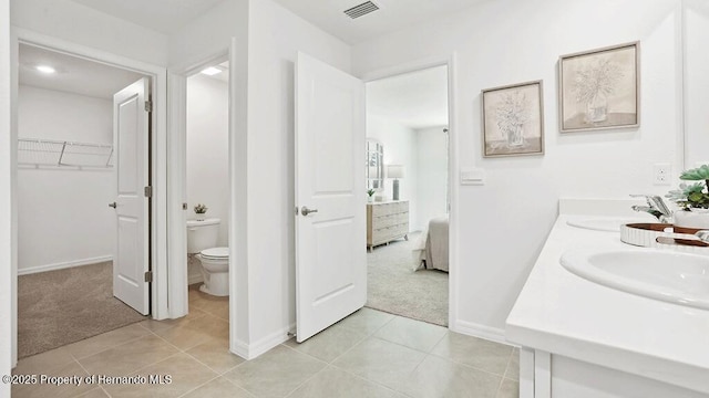 ensuite bathroom featuring tile patterned flooring, visible vents, toilet, and a sink