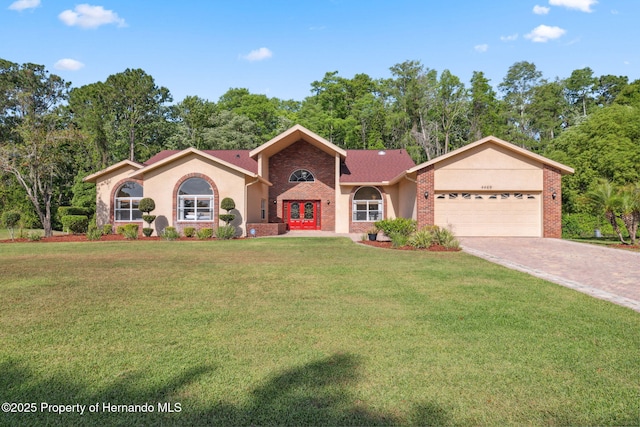 4469 Lake In The Woods Dr, Weeki Wachee, FL 34607 - view of front of home featuring stucco siding, a front yard, driveway, and an attached garage