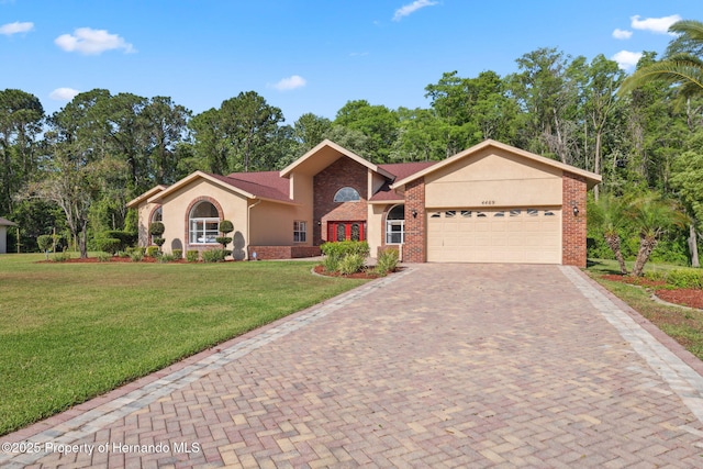 4469 Lake In The Woods Dr, Weeki Wachee, FL 34607 - view of front of home with stucco siding, brick siding, decorative driveway, a garage, and a front lawn
