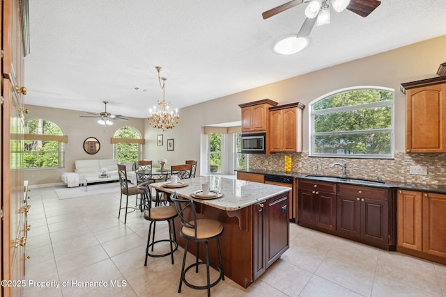 4469 Lake In The Woods Dr, Weeki Wachee, FL 34607 - kitchen with stainless steel microwave, a healthy amount of sunlight, decorative backsplash, and ceiling fan with notable chandelier
