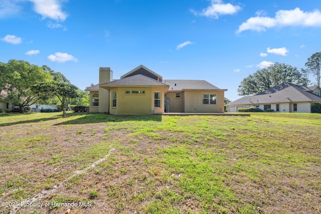 4469 Lake In The Woods Dr, Weeki Wachee, FL 34607 - back of property featuring a chimney, stucco siding, and a lawn