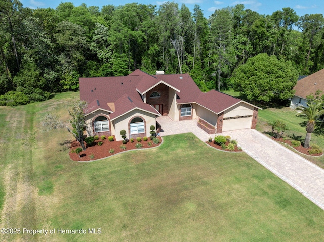4469 Lake In The Woods Dr, Weeki Wachee, FL 34607 - view of front facade with a front lawn, driveway, brick siding, and a view of trees