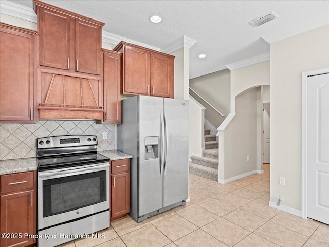 kitchen featuring appliances with stainless steel finishes, ornamental molding, tasteful backsplash, arched walkways, and light stone counters