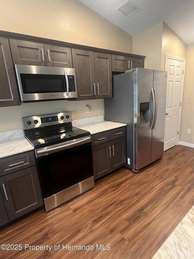 15297 Myland Rd, Weeki Wachee, FL 34614 - kitchen with dark wood-style flooring, stainless steel appliances, visible vents, light stone counters, and lofted ceiling