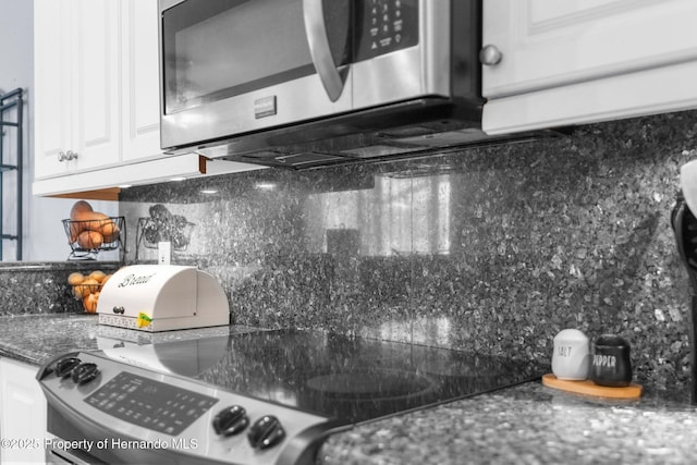 9208 Butler Blvd, Weeki Wachee, FL 34613 - kitchen featuring stainless steel microwave, white cabinets, and backsplash