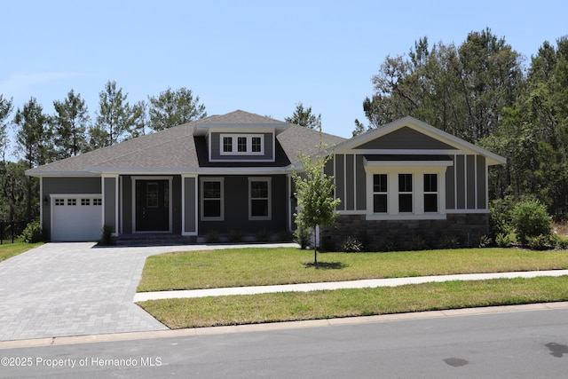 6063 Dusk Rose Ln, Brooksville, FL 34601 - view of front of house featuring decorative driveway, an attached garage, a front lawn, stone siding, and a porch
