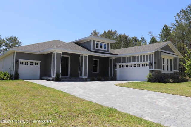 6063 Dusk Rose Ln, Brooksville, FL 34601 - view of front of house with a garage, a front lawn, roof with shingles, covered porch, and driveway