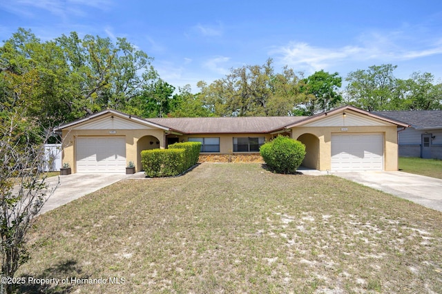 single story home with stucco siding, a front lawn, concrete driveway, and an attached garage