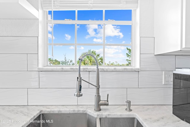 details featuring white cabinets, light stone counters, decorative backsplash, and a sink