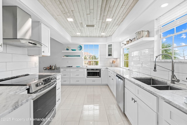 kitchen featuring open shelves, appliances with stainless steel finishes, wall chimney exhaust hood, and tasteful backsplash